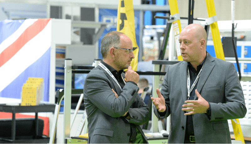 2 professionals in business attire engaged in a discussion at IMHX